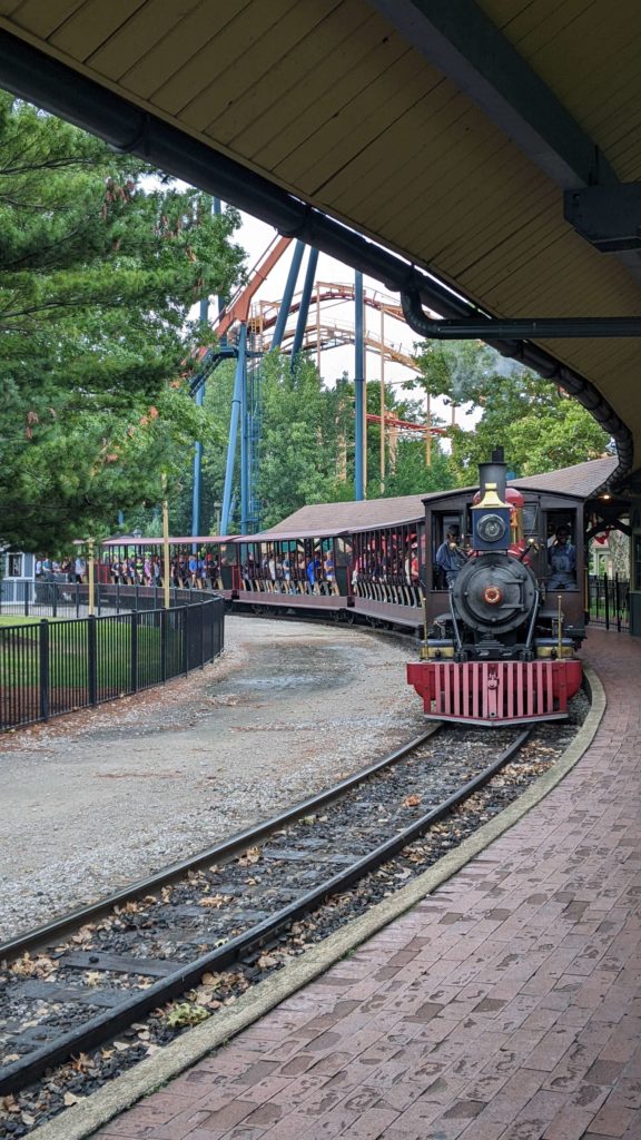 A black and red train heading directly towards the camera with a curved track that veers to the left.